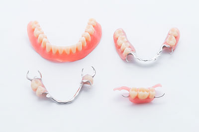 The image displays three sets of fake teeth with silver brackets against a white background.