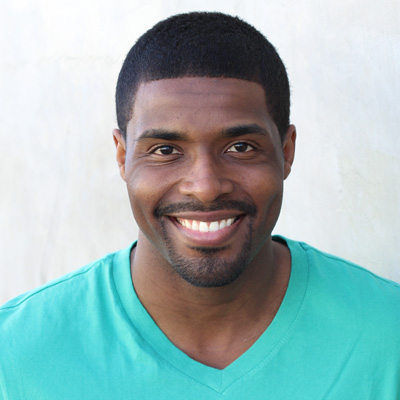 An elderly couple sharing a warm embrace, both smiling, with the man wearing a beard and the woman in a blue scarf.